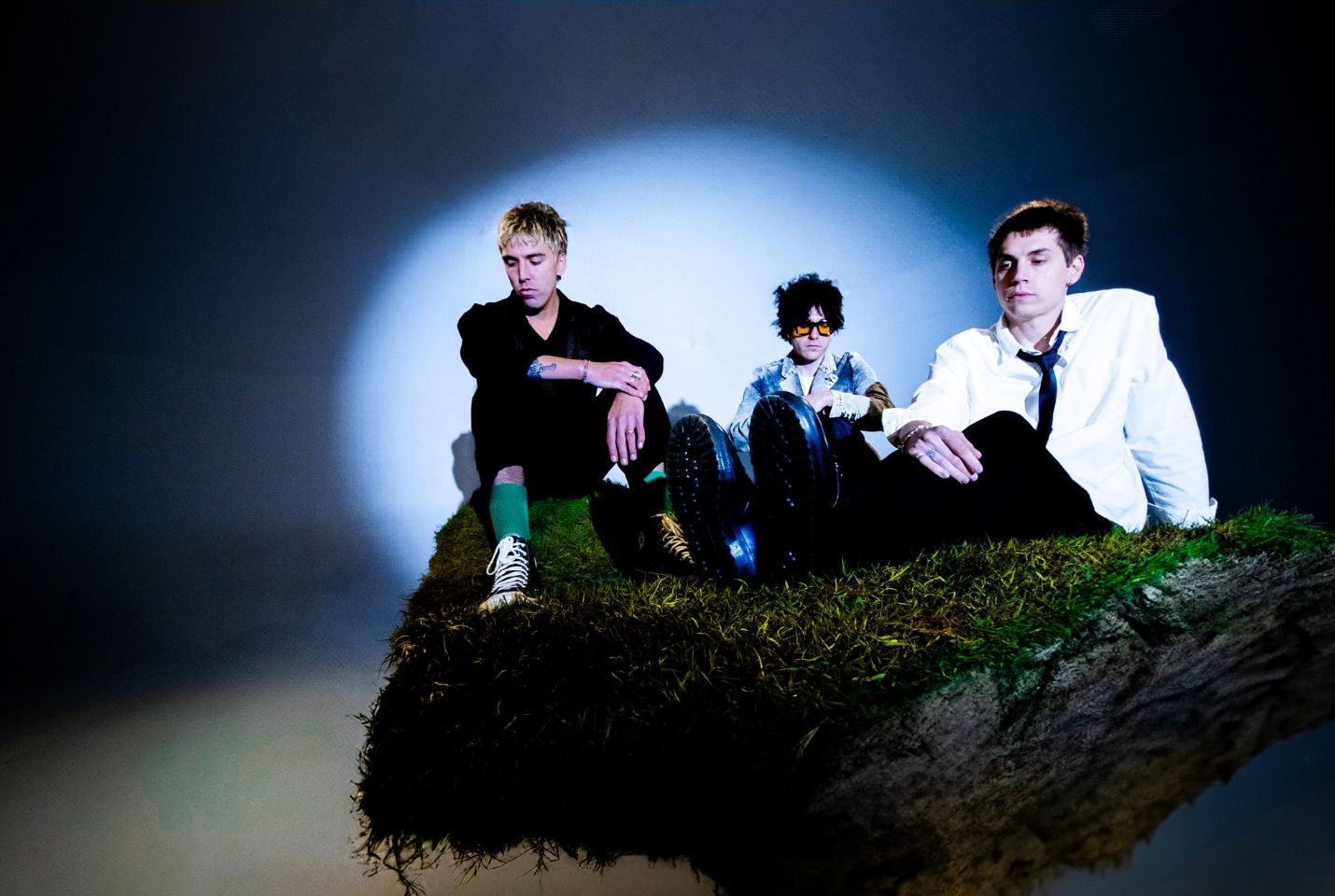 3 men posing on mossy rock with spotlight on them